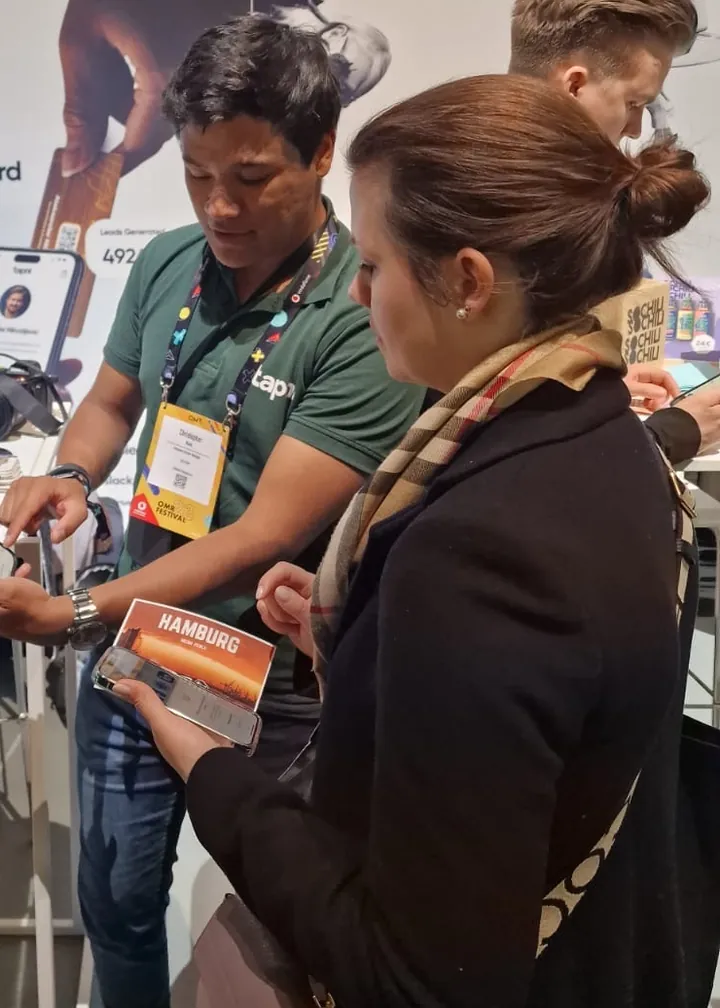 Tapni team member showing a visitor a digital business card profile on her phone at a trade-show booth