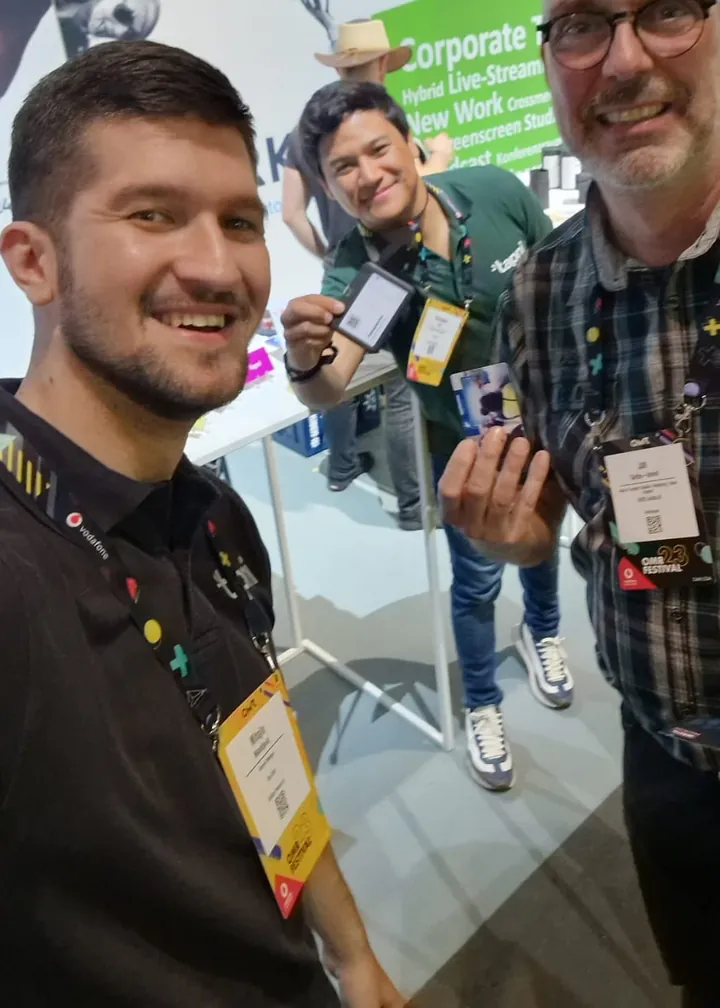 Tapni team and a visitor holding up their Tapni cards at a startup event